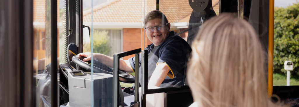 Female bus driver welcoming customers onto bus